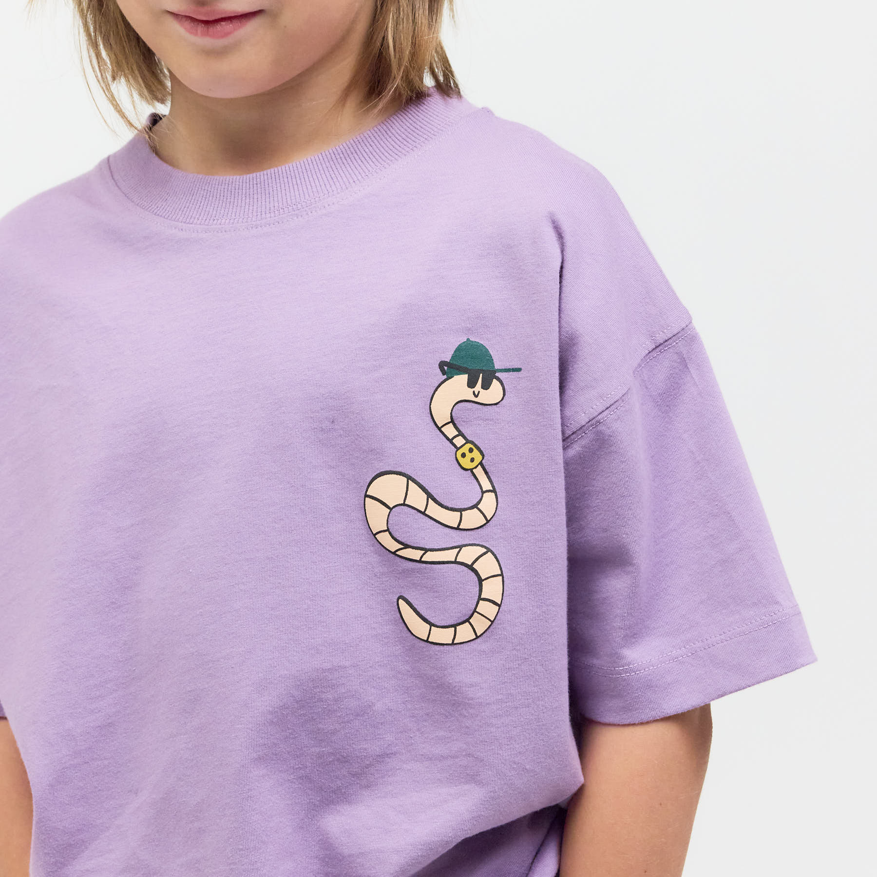 Junge trägt das fliederfarbene Checker Tobi T-Shirt mit Regenurm-Grafik – bequemer Relaxed Fit, der mehr als nur Merch bietet.