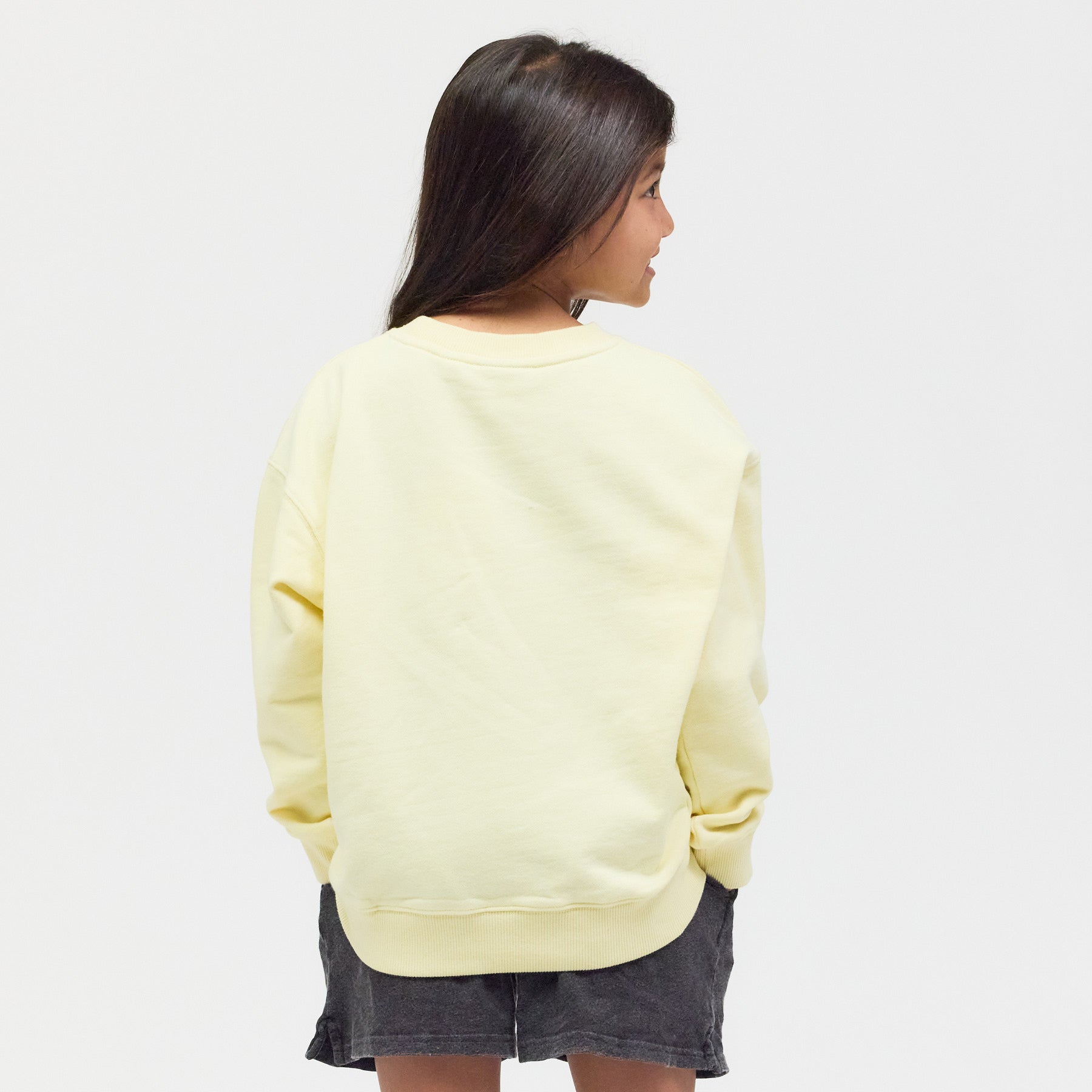 Rückansicht des gelben Sweatshirts am Model – zeitloses Design, das mehr als nur Merch bietet, fair und nachhaltig produziert in Portugal.