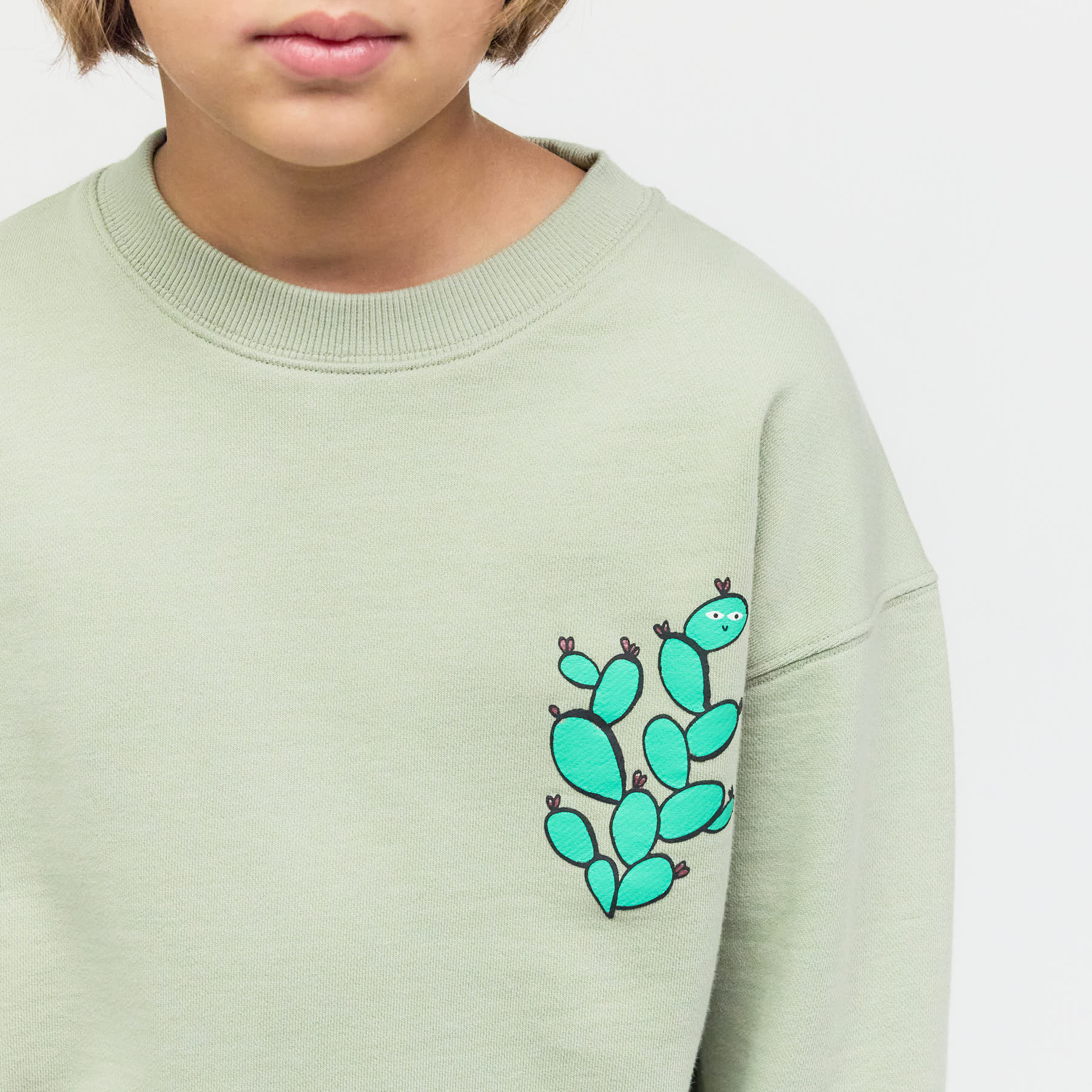 Nahaufnahme des Kaktus-Siebdrucks auf salbeigrünem Bio-Stoff – schadstofffreie Veredelung statt einfachem Fan-Merch.