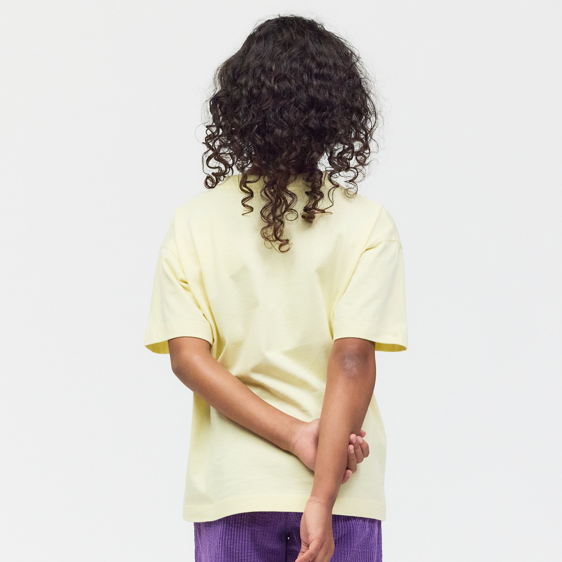 Rückseite des hellgelben Shirts am Model – bequemer Unisex-Schnitt in Premium-Qualität.